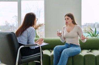 Psikoterapist psikolog, sosyal psikolog, profesyonel uzman ofisinde terapi gören üzgün, genç bir kadın. Gençlik psikolojisinin zihinsel sağlığı sorunları, danışmanlık