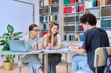 Bir grup öğrenci lise çağında sınıf kütüphanesinde birlikte oturmuş sınavlara hazırlanıyorlar. Eğitim, öğrenme, bilgi, gençlik kavramı