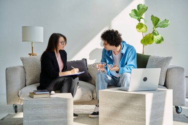 Zihinsel terapi seansı, kadın psikolog, terapist, sosyal hizmet görevlisi ile konuşan genç adam ofiste birlikte oturuyor. Psikoloji Psikiyatri Danışmanlık Destek Gençlere Yardım