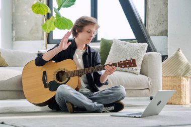 Akustik gitar dizüstü bilgisayarı olan genç bir çocuk bilgisayar ekranına el sallıyor, çevrimiçi müzik dersi alıyor, müzik blogu kaydediyor, takipçilerle iletişim kuran genç bir nüfuz sahibi. Yaşam tarzı, ergenlik.