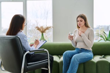 Psikoterapist psikolog, sosyal psikolog, profesyonel uzman ofisinde terapi gören üzgün, genç bir kadın. Gençlik psikolojisinin zihinsel sağlığı sorunları, danışmanlık