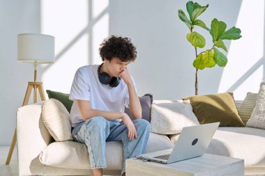 Genç, yakışıklı, ciddi adam evdeki kanepede oturan dizüstü bilgisayara bakıyor. Boş zamanlarında çalışma iletişim teknolojileri, yaşam tarzı, gençlik kavramı