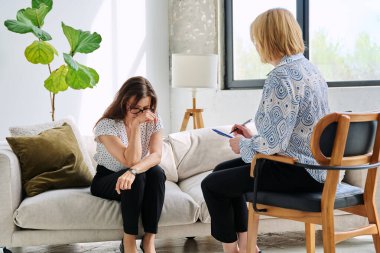 Mutsuz, üzgün, orta yaşlı kadın terapi seansında psikolog, ruh sağlığı muayenehanesinde olgun hastalara destek oluyor. Psikoloji Psikoterapi Psikiyatri Danışmanlık Konsepti