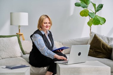 Ofisteki koltukta oturan dizüstü bilgisayarla çevrimiçi seans yapan profesyonel bir kadın psikolog. Video toplantısı, uzaktan terapi, psikoloji, psikoterapi, ruh sağlığı hizmeti, teknoloji