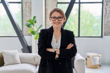 Siyah takım elbiseli, kameraya bakan orta yaşlı bir iş kadınının portresi. Ofiste çapraz kollu 40 'lı yaşlarda kendinden emin bir kadın. İş yönetimi kariyeri olgun insanlar