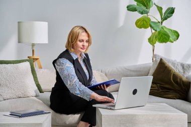 Ofisteki koltukta oturan dizüstü bilgisayarla çevrimiçi seans yapan profesyonel bir kadın psikolog. Video toplantısı, uzaktan terapi, psikoloji, psikoterapi, ruh sağlığı hizmeti, teknoloji