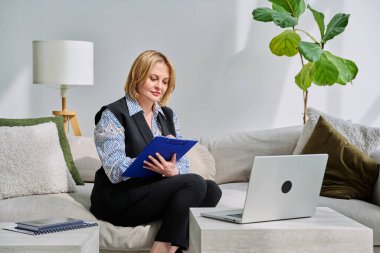 Ofisteki koltukta oturan dizüstü bilgisayarla çevrimiçi seans yapan profesyonel bir kadın psikolog. Video toplantısı, uzaktan terapi, psikoloji, psikoterapi, ruh sağlığı hizmeti, teknoloji