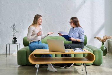 Terapi seansında genç ve gülümseyen kadın hasta psikolog sosyal terapist ile birlikte kanepede oturuyor. Sağlık hizmetleri gençlik yardımı, psikolojik hizmetler, psikoterapi kavramı