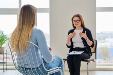 Orta yaşlı kadın psikolog psikoterapist kadın hasta ile çalışıyor. Zihin uzmanı, sosyal hizmetler görevlisi. Tedavi psikoloji psikoterapi danışmanlığına yardımcı olur
