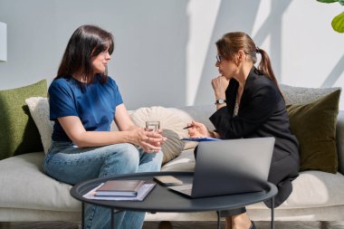 Zihinsel terapi seansı, genç kadın hasta profesyonel psikolog psikoterapist zihinsel terapistle konuşuyor, kanepede yan yana oturuyor. Psikoloji psikoterapi danışmanlık konsepti