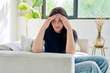 Evdeki kanepede oturan mutsuz genç kadın. Depresyon, stres, acı, sorunlar, akıl sağlığı insanları kavramı