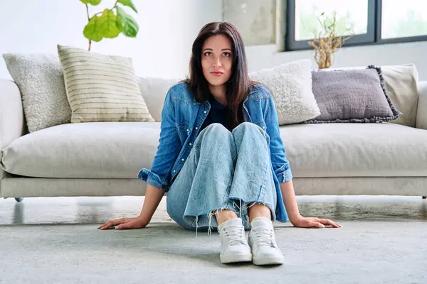 Oturma odasındaki kanepenin yanında oturan güzel, mutlu, esmer kadının portresi. 30 'lu yaşlarda çekici bir kadın kameraya bakıyor. Güzellik, yaşam tarzı, kadın konsepti