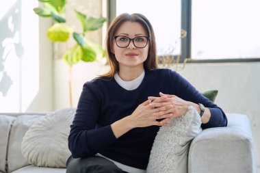 Orta yaşlı, güzel bir kadının portresi. Kanepede oturuyor. Gözlüklü, çekici, olgun bir kadın. Güzellik, sağlık, yaşam tarzı, insan kavramı