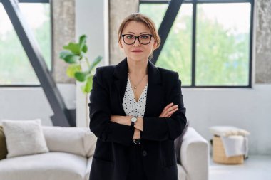 Siyah takım elbiseli, kameraya bakan orta yaşlı bir iş kadınının portresi. Ofiste çapraz kollu 40 'lı yaşlarda kendinden emin bir kadın. İş yönetimi kariyeri olgun insanlar