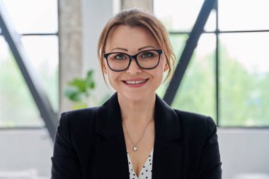 Ofiste kameraya bakan orta yaşlı bir iş kadınının portresi. Siyah takım elbiseli 40 'lı yaşlarda kendinden emin bir kadın. İş yönetimi kariyeri olgun insanlar konsepti