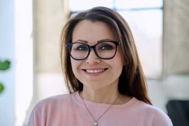 Evinde, mutlu, gülümseyen, orta yaşlı, gözlüklü bir kadının portresi. Güzellik, başarı, iş, olgun yaş insanları konsepti