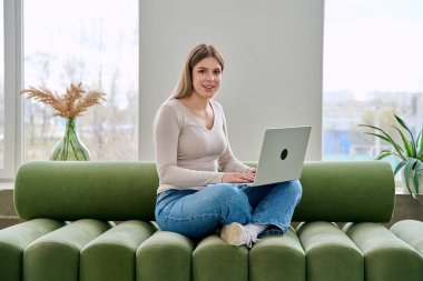 Genç bir kadının portresi kanepeye oturmuş iç dizüstü bilgisayarla kameraya bakıyor. Üniversite öğrencisi sınava hazırlanıyor, bilgisayar başında yazı yazıyor, rahatlıyor sosyal medya blogunu okuyor.