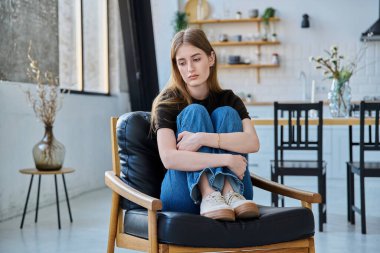 Üzgün, mutsuz, genç bir kadın koltuğunda oturuyor. Gençlik sağlığı, üzüntü, sorunlar depresyon, acı kavramı