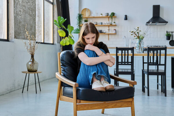 Sad stressed unhappy young woman sitting at home on the armchair. Youth mental health, sadness, problems difficulties depression pain concept
