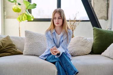 Üzgün, hayal kırıklığına uğramış, 17-18 yaşlarında bir genç kız evinde kanepede oturuyor. Stres, depresyon, gençlik, gençlik krizi, gençlerin akıl sağlığı konsepti