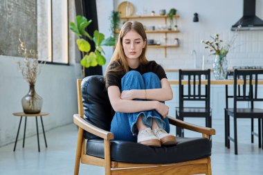 Üzgün, mutsuz, genç bir kadın koltuğunda oturuyor. Gençlik sağlığı, üzüntü, sorunlar depresyon, acı kavramı