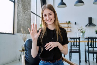 Web kamera görüntüsü genç üniversite öğrencisinin kameraya bakıp el salladığını internetteki görüntülü sohbet konferansını gösteriyor. Genç bayan blogger vlog kaydedici evde video kaydediliyor