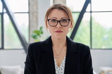 Ofisteki kameraya bakan orta yaşlı ciddi bir iş kadınının portresi. Siyah takım elbiseli 40 'lı yaşlarda kendinden emin bir kadın. İş yönetimi kariyeri olgun insanlar konsepti