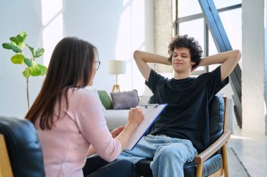 Zihinsel terapi seansında gülümseyen genç erkek hasta uzman psikolog psikoterapist danışman sosyal hizmet görevlisiyle konuşuyor. Hizmet psikolojisi psikoterapi desteği