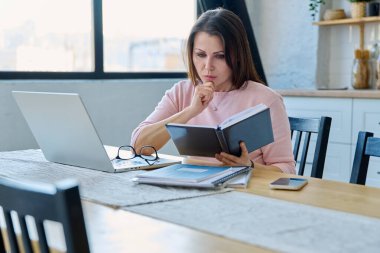 Merkez ofisteki bilgisayar bilgisayarında çalışan orta yaşlı ciddi bir kadın. Olgun bir kadın masada oturmuş monitöre bakarak yazı yazıyor. Uzak iş, öğretim, iş, blog, serbest konsept