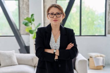 Siyah takım elbiseli, kameraya bakan orta yaşlı bir iş kadınının portresi. Ofiste çapraz kollu 40 'lı yaşlarda kendinden emin bir kadın. İş yönetimi kariyeri olgun insanlar