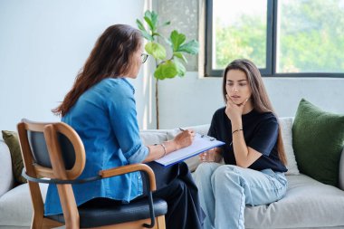 Üzgün, mutsuz kız öğrenci 17, 18, 19 yaşlarında profesyonel sosyal psikolog, terapist, danışman ile konuşuyor. Psikoloji, psikoterapi, akıl sağlığı, terapi, ergenlik konsepti.