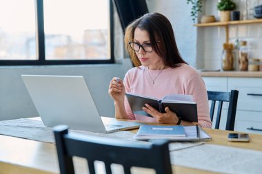 Merkez ofisteki bilgisayar bilgisayarında çalışan orta yaşlı ciddi bir kadın. Olgun bir kadın masada oturmuş monitöre bakarak yazı yazıyor. Uzak iş, öğretim, iş, blog, serbest konsept