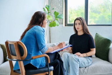 Üzgün, mutsuz kız öğrenci 17, 18, 19 yaşlarında profesyonel sosyal psikolog, terapist, danışman ile konuşuyor. Psikoloji, psikoterapi, akıl sağlığı, terapi, ergenlik konsepti.