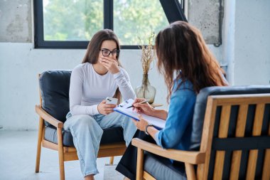 Üzgün, mutsuz kız öğrenci 17, 18, 19 yaşlarında profesyonel sosyal psikolog, terapist, danışman ile konuşuyor. Psikoloji, psikoterapi, akıl sağlığı, terapi, ergenlik konsepti.