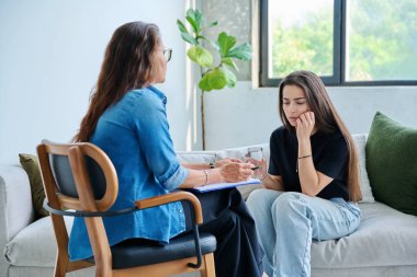 Üzgün, mutsuz kız öğrenci 17, 18, 19 yaşlarında profesyonel sosyal psikolog, terapist, danışman ile konuşuyor. Psikoloji, psikoterapi, akıl sağlığı, terapi, ergenlik konsepti.