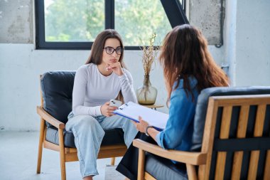 Üzgün, mutsuz kız öğrenci 17, 18, 19 yaşlarında profesyonel sosyal psikolog, terapist, danışman ile konuşuyor. Psikoloji, psikoterapi, akıl sağlığı, terapi, ergenlik konsepti.