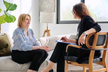 Zihinsel terapi seansı, orta yaşlı iş kadını hasta profesyonel psikolog psikoterapist zihinsel terapistle konuşuyor, ofiste birlikte oturuyorlar. Psikoloji psikoterapi danışmanlık konsepti