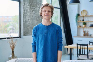 Evde kendine güvenen gülümseyen bir gencin portresi. Yakışıklı sarışın adam kameraya bakıyor. Gençlik yaşı, 16-17 yaş arası, ergen, yaşam tarzı, eğlence konsepti