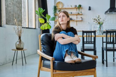 Üzgün, mutsuz, genç bir kadın koltuğunda oturuyor. Gençlik sağlığı, üzüntü, sorunlar depresyon, acı kavramı