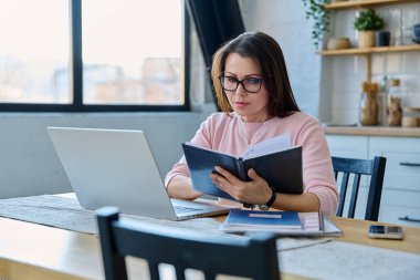 Merkez ofisteki bilgisayar bilgisayarında çalışan orta yaşlı ciddi bir kadın. Olgun bir kadın masada oturmuş monitöre bakarak yazı yazıyor. Uzak iş, öğretim, iş, blog, serbest konsept