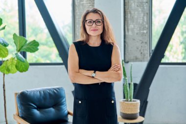 Siyah takım elbiseli, kameraya bakan orta yaşlı bir iş kadınının portresi. Ofiste çapraz kollu 40 'lı yaşlarda kendinden emin bir kadın. İş yönetimi kariyeri olgun insanlar
