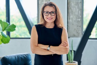 Siyah takım elbiseli, kameraya bakan orta yaşlı bir iş kadınının portresi. Ofiste çapraz kollu 40 'lı yaşlarda kendinden emin bir kadın. İş yönetimi kariyeri olgun insanlar