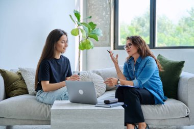 Terapi seansında genç gülümseyen kız hasta psikolog sosyal terapist ile birlikte kanepede oturuyor. Sağlık hizmeti gençlik yardımı, psikolojik hizmetler, psikoterapi