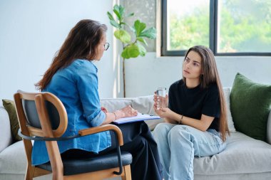 Üzgün, mutsuz kız öğrenci 17, 18, 19 yaşlarında profesyonel sosyal psikolog, terapist, danışman ile konuşuyor. Psikoloji, psikoterapi, akıl sağlığı, terapi, ergenlik konsepti.