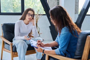 Üzgün, mutsuz kız öğrenci 17, 18, 19 yaşlarında profesyonel sosyal psikolog, terapist, danışman ile konuşuyor. Psikoloji, psikoterapi, akıl sağlığı, terapi, ergenlik konsepti.