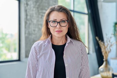 Ofisteki kameraya bakan orta yaşlı bir iş kadınının portresi. Gözlüklü 40 'lı yaşlarda kendine güvenen güzel bir kadın. İş yönetimi kariyeri olgun insanlar konsepti