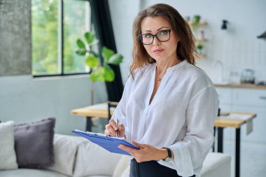 Kendine güvenen orta yaşlı iş kadını portresi pano ile poz veriyor. Başarılı, profesyonel, olgun kadın psikolog zihinsel terapist danışman yönetici danışman koltukta.