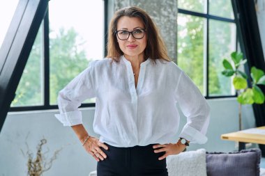 Beyaz gömlekli, gözlüklü, kameraya bakan orta yaşlı güzel bir iş kadını portresi. 40 'lı yaşlarda başarılı bir kadın. İş yönetimi kariyeri olgun insanlar