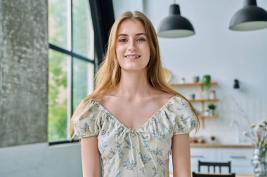 18-20 yaşlarındaki güzel sarışın bir kadının portresi. Evin içindeki kameraya bakıyor. İnsanlar, gençlik yaşı, güzellik, sağlık, yaşam tarzı kavramı