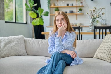 Üzgün, üzgün, üzgün, genç bir kadın. Kanepede oturuyor. Yüzü yakın plan. Duygular, sorunlar, ilişkilerde zorluklar, öğrenim, aile